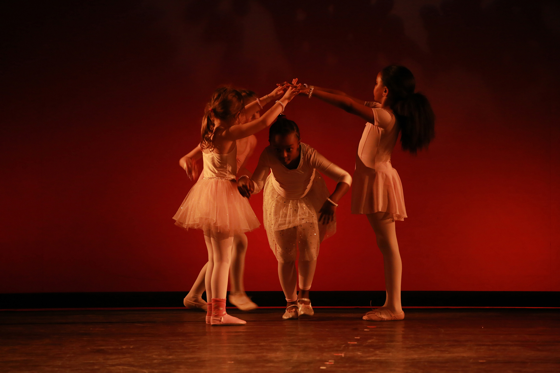 Junge Ballettschülerinnen tanzen anmutig in rosa Tutus auf der Bühne des Tanzstudios München.