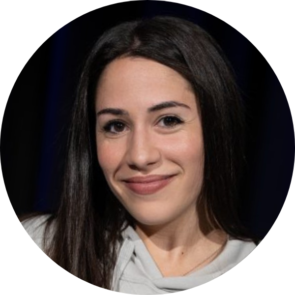 Rundes Portrait einer Hip-Hop-Trainerin mit langen dunklen Haaren und hellem Hoodie vor dunklem Hintergrund.