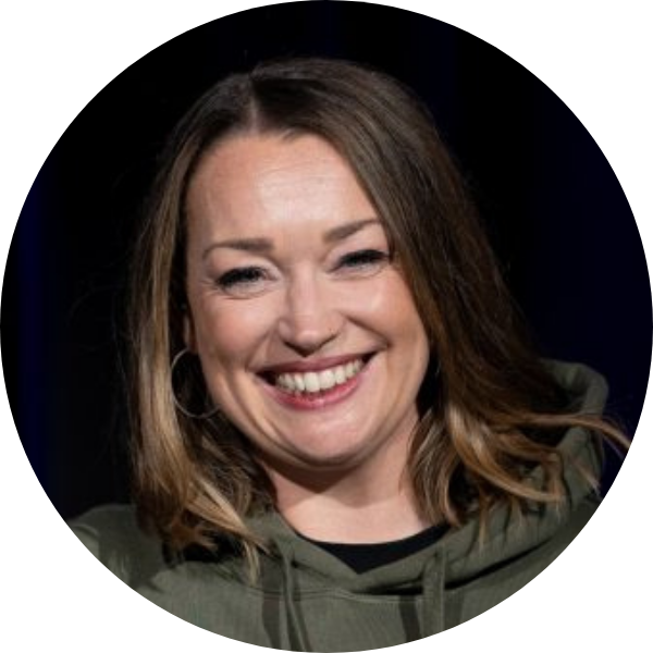 Rundes Portrait einer lächelnden Hip-Hop-Trainerin im grünen Hoodie mit Bühnenlicht auf dunklem Hintergrund.