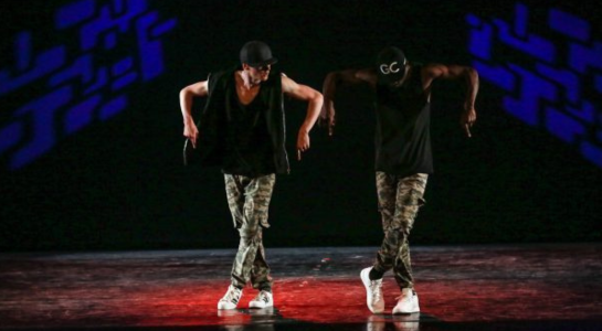 Zwei Tänzer führen synchron eine Hip-Hop-Choreografie auf der Bühne auf