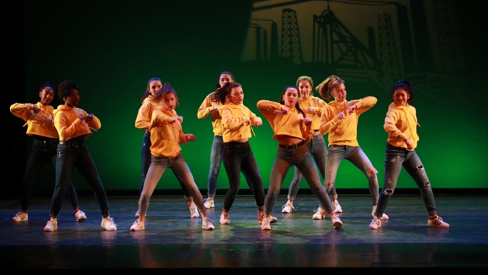 Jugendliche tanzen eine energiegeladene Hip-Hop Choreografie auf der Bühne – ideal für alle, die hip hop tanzen Jugendliche lernen möchten.