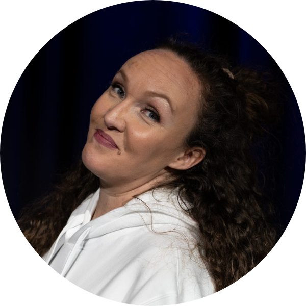 Jessy Sella, Tanzlehrerin für Bauchtanz und Orientalische Tanzfusion bei KayJay’s Dance Studio München, lächelt vor dunklem Hintergrund.