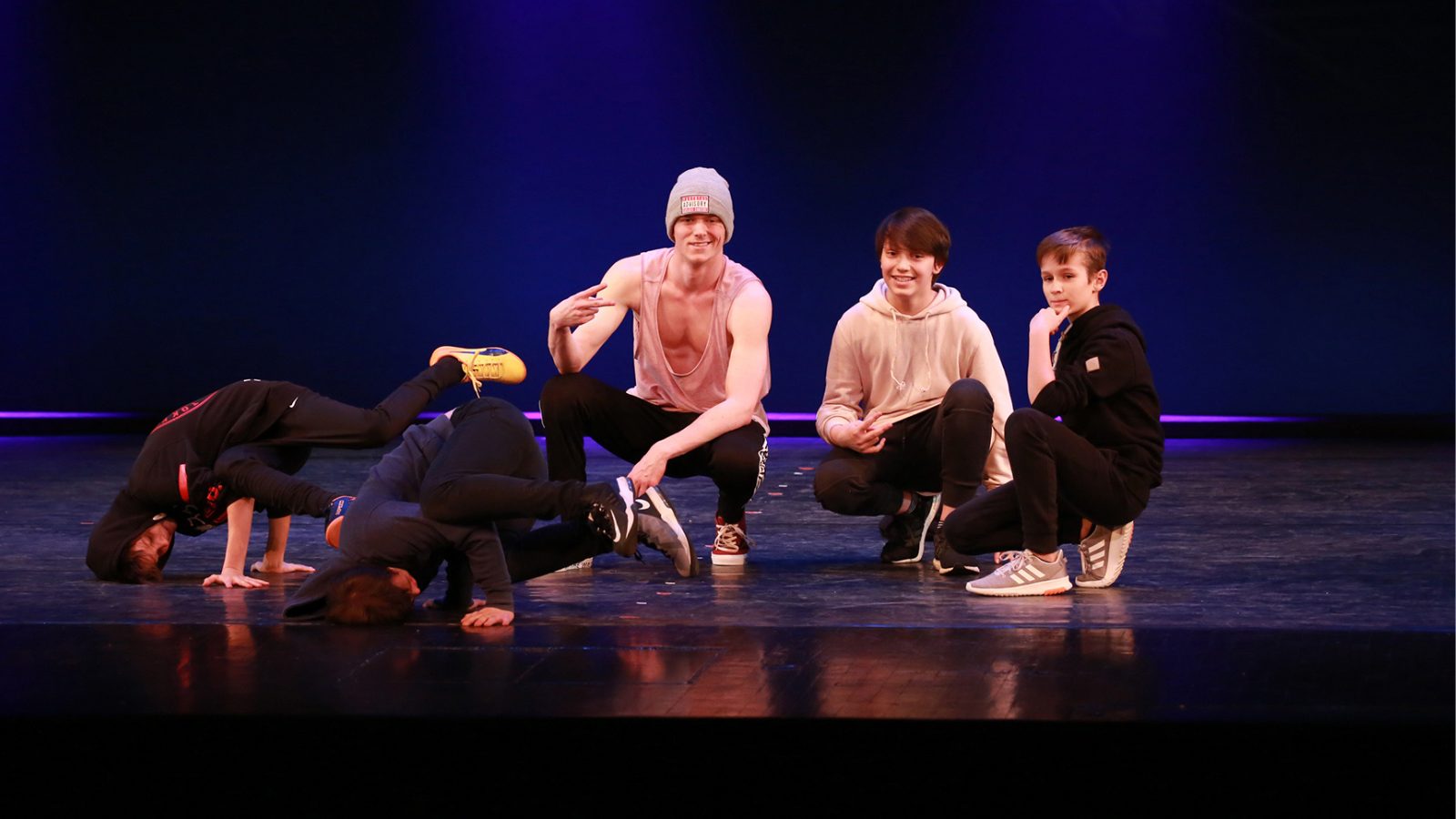 Breakdance Kurs in München bei KayJay’s: Trainer Paul Westerhoff posiert mit seinen Schülern auf der Bühne, während Kinder verschiedene Breaking-Posen und Freezes zeigen.