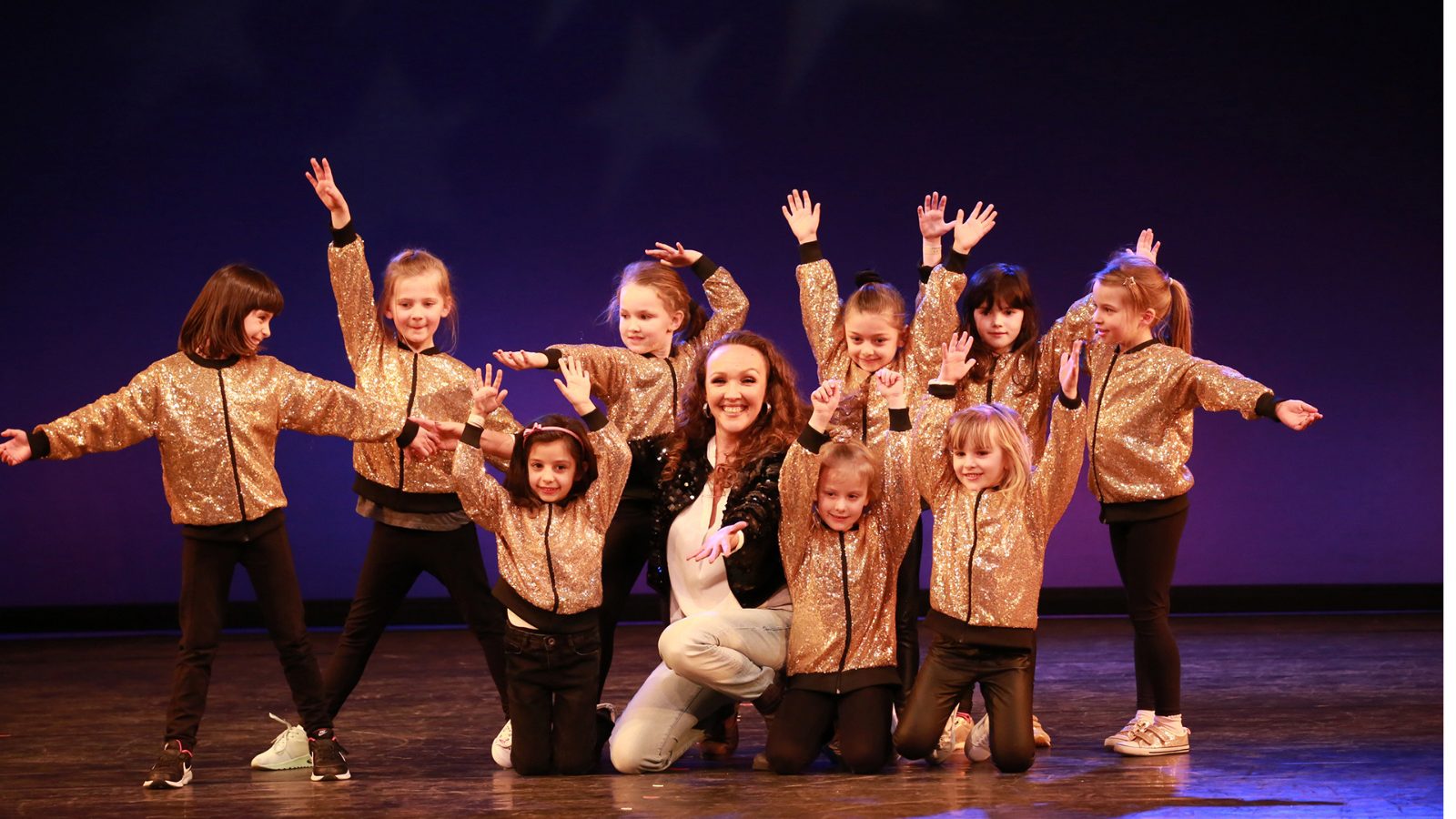 Gruppe von Kindern in goldenen Jacken tanzt auf der Bühne beim Kindertanz in München im KayJay’s Dance Center.
