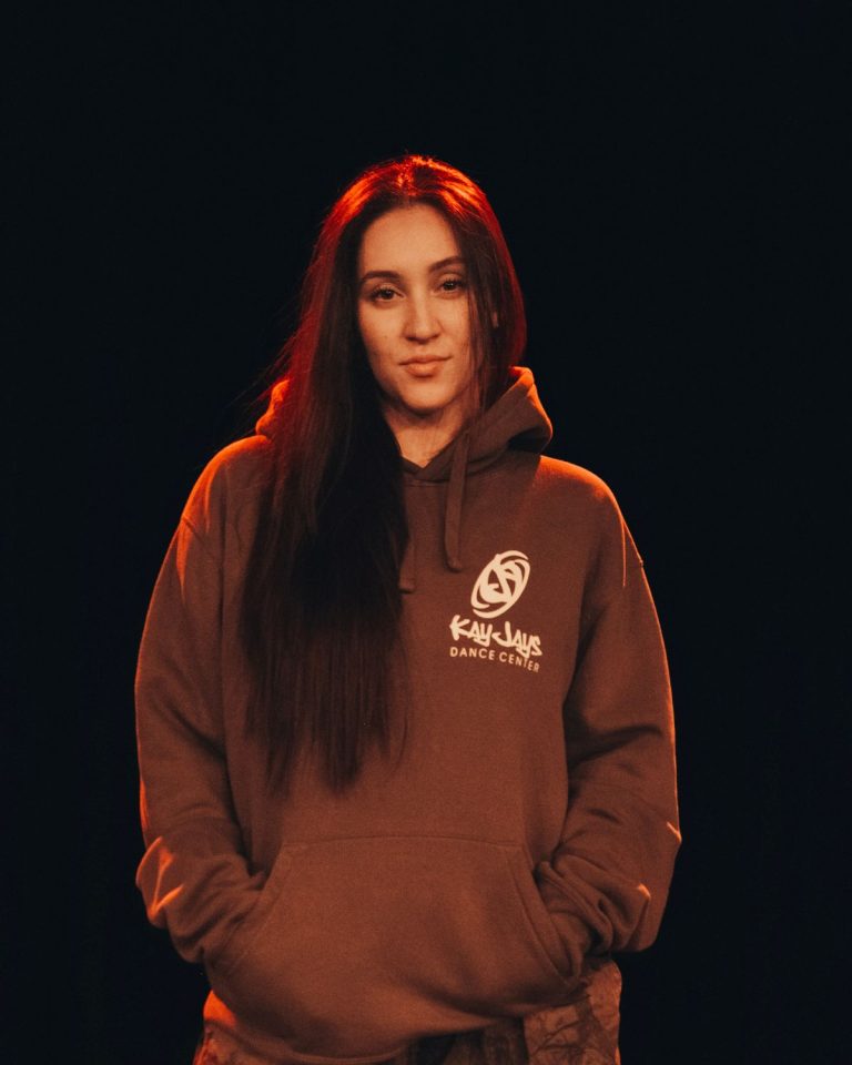 Eleni, Trainerin bei KayJays, im braunen KayJays-Hoodie im roten Streiflicht