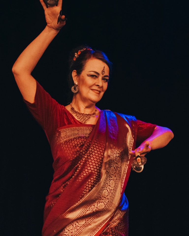 Katharina, Trainerin bei KayJays, im rot-goldenen Sari in einer Tanzpose